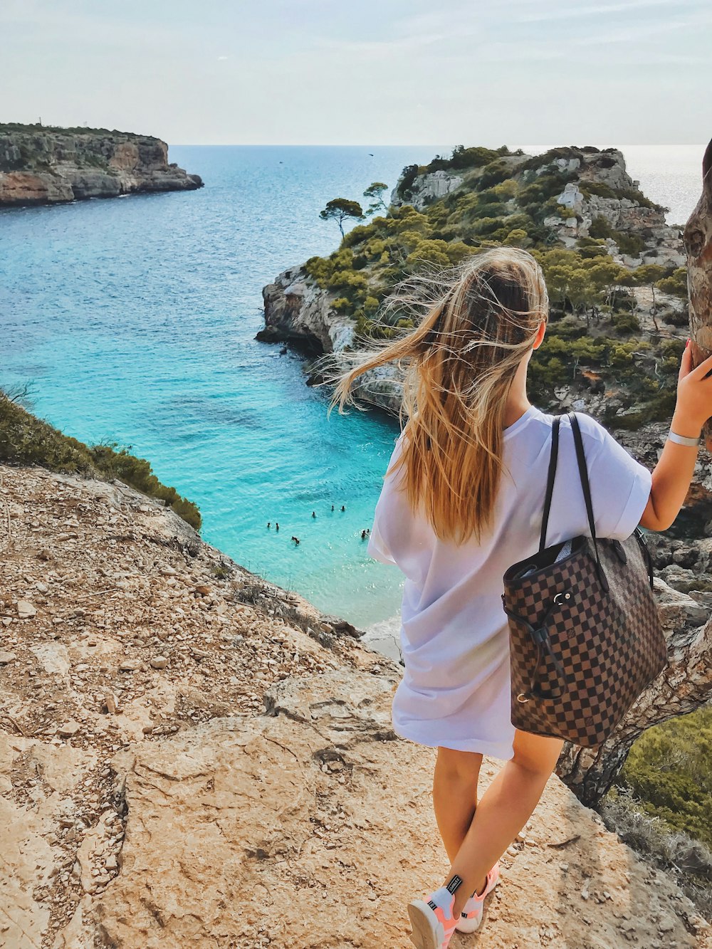 a woman with a handbag looking at the ocean