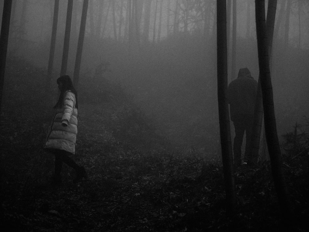 grey scale photography of man and woman standing on forest