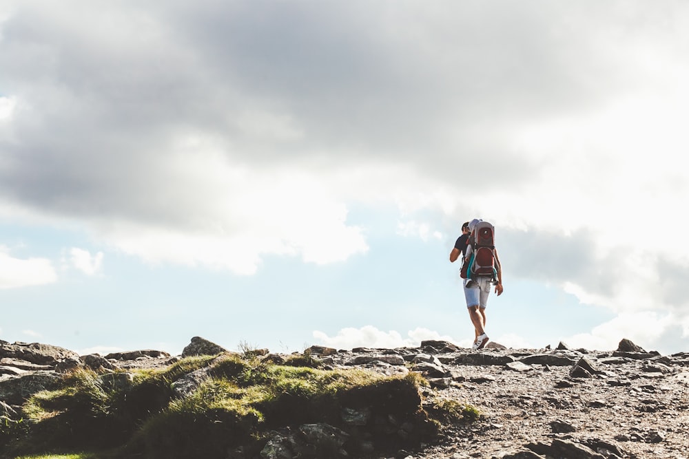 man in white shorts walking on rocky road under white sky during daytime