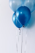 four blue balloons near white wall