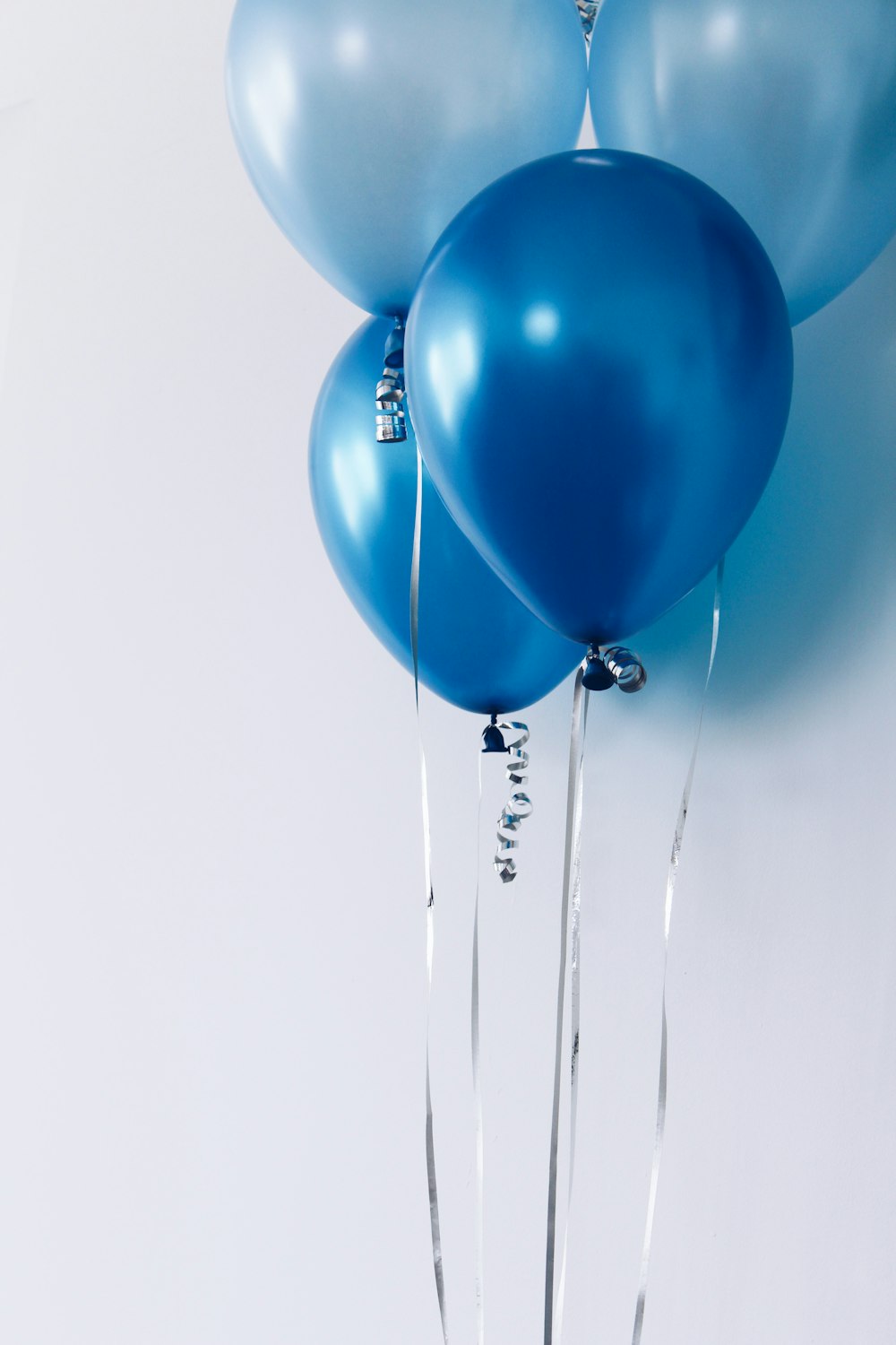 Vier blaue Luftballons in der Nähe einer weißen Wand