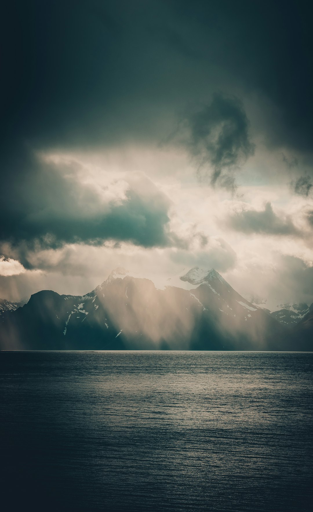 calm sea surrounded by mountain under white sky