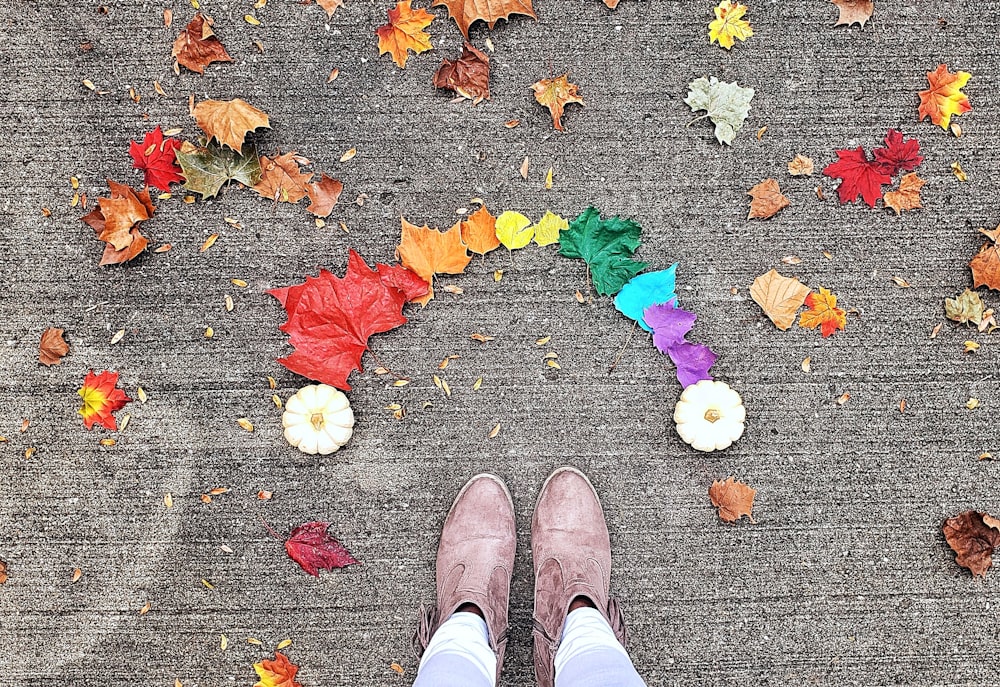 pessoa usando botas marrons em pé perto de folhas