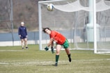 A passionate football player in red jersey scoring a goal during a lively match.