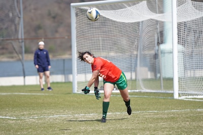 A passionate football player in red jersey scoring a goal during a lively match.