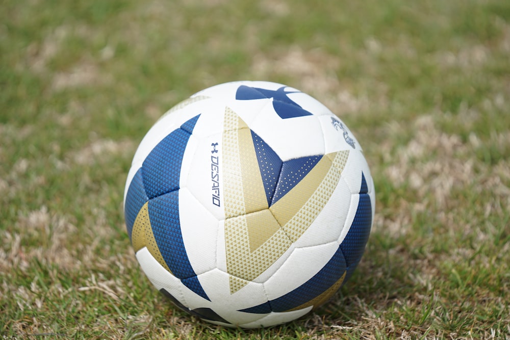 white and blue Under Armour soccer ball on green field