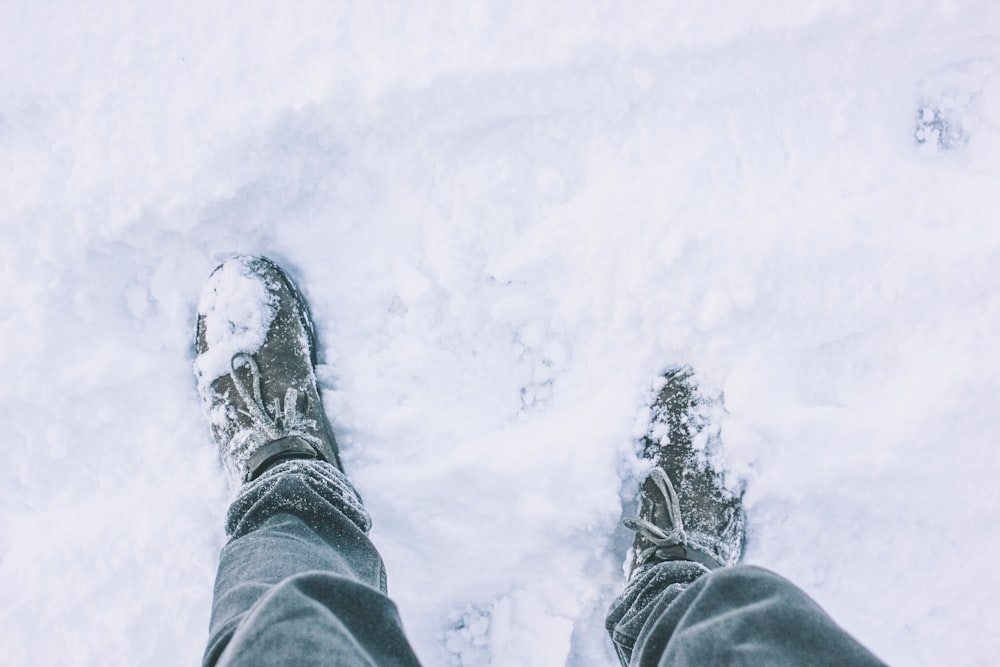 une personne debout dans la neige, les pieds dans la neige