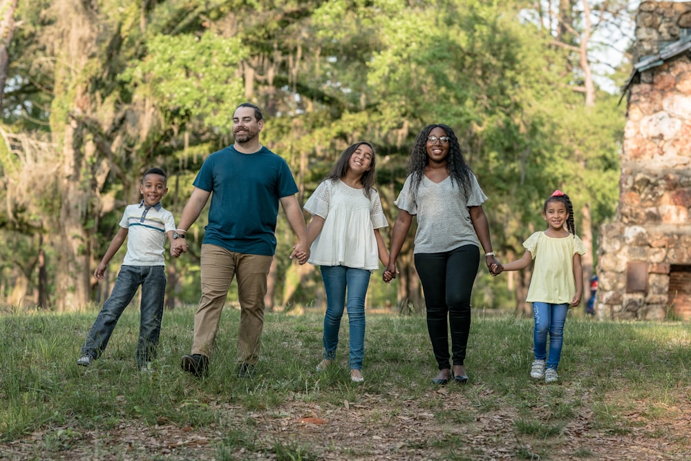 family of five standing near trees during daytime