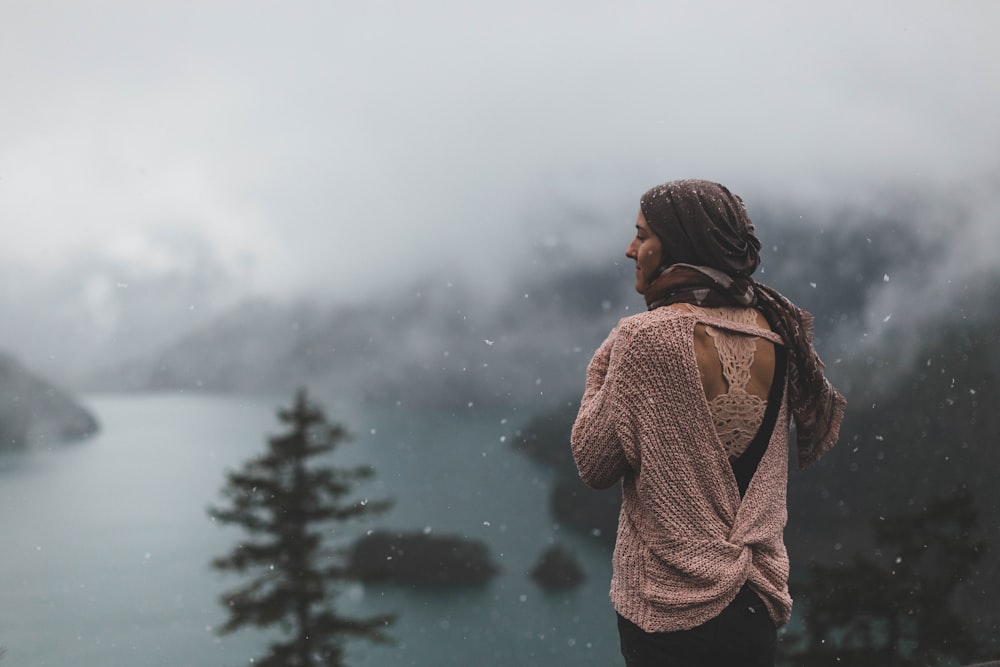 woman standing near lake surrounded with trees