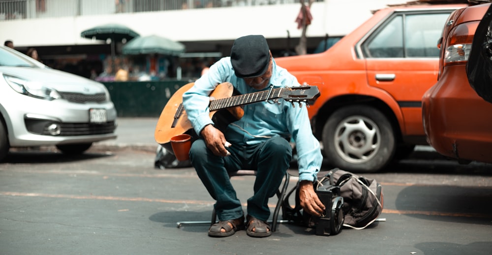 Mann sitzt auf der Straße und hält Gitarre in der Hand