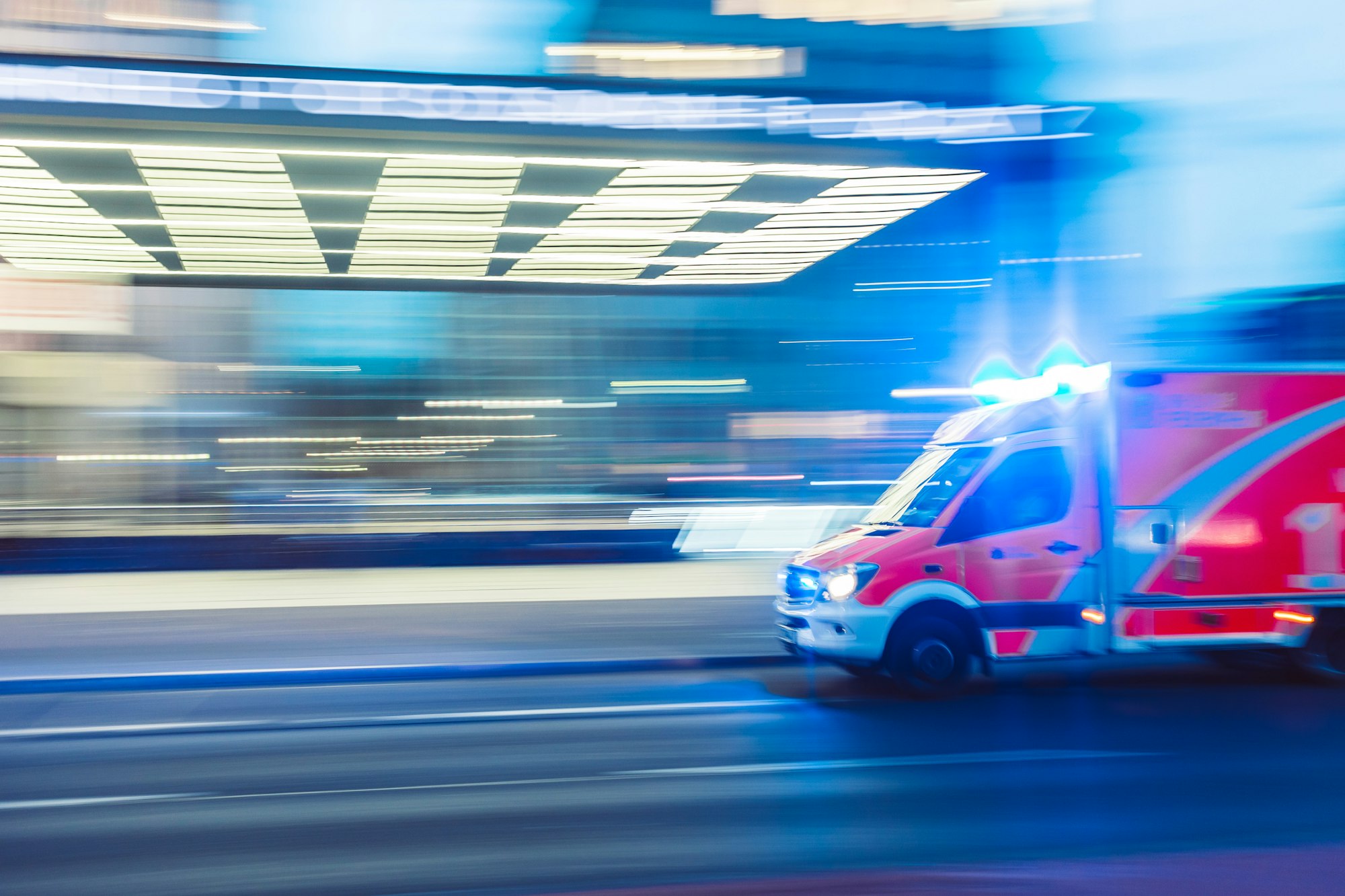 An ambulance rushes to respond to an emergency with blue lights flashing.