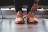 A close-up of disciplined hands tying running shoes on a charcoal-colored floor, ready for a morning workout.