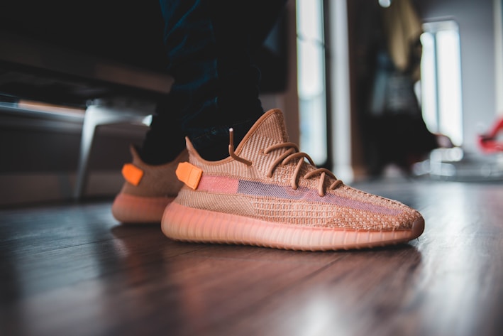 A close-up of a stylish, comfortable sneaker on a wooden floor.
