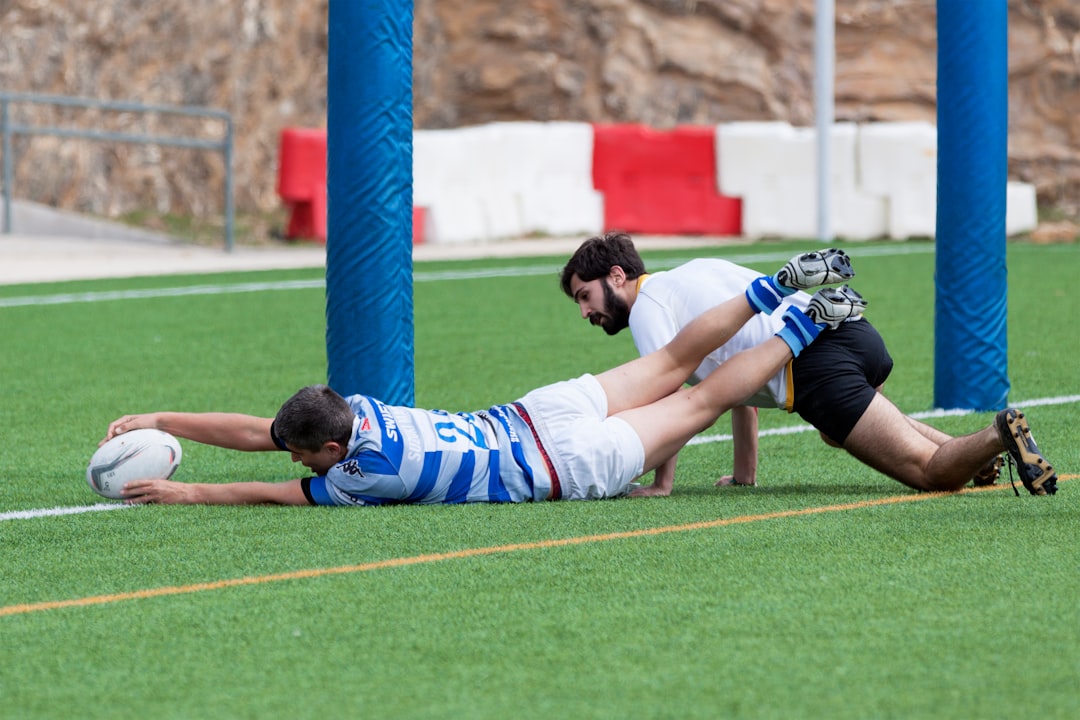 two men playing football at green field