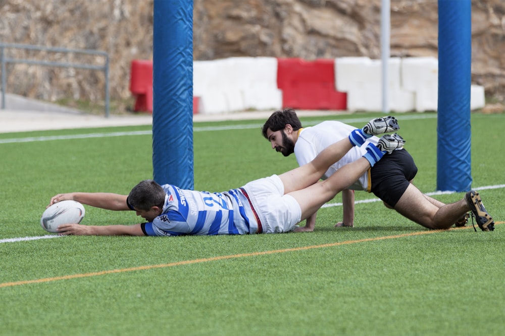 two men playing football at green field