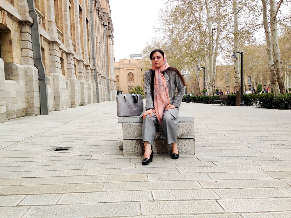 woman sitting on bench beside buildilng