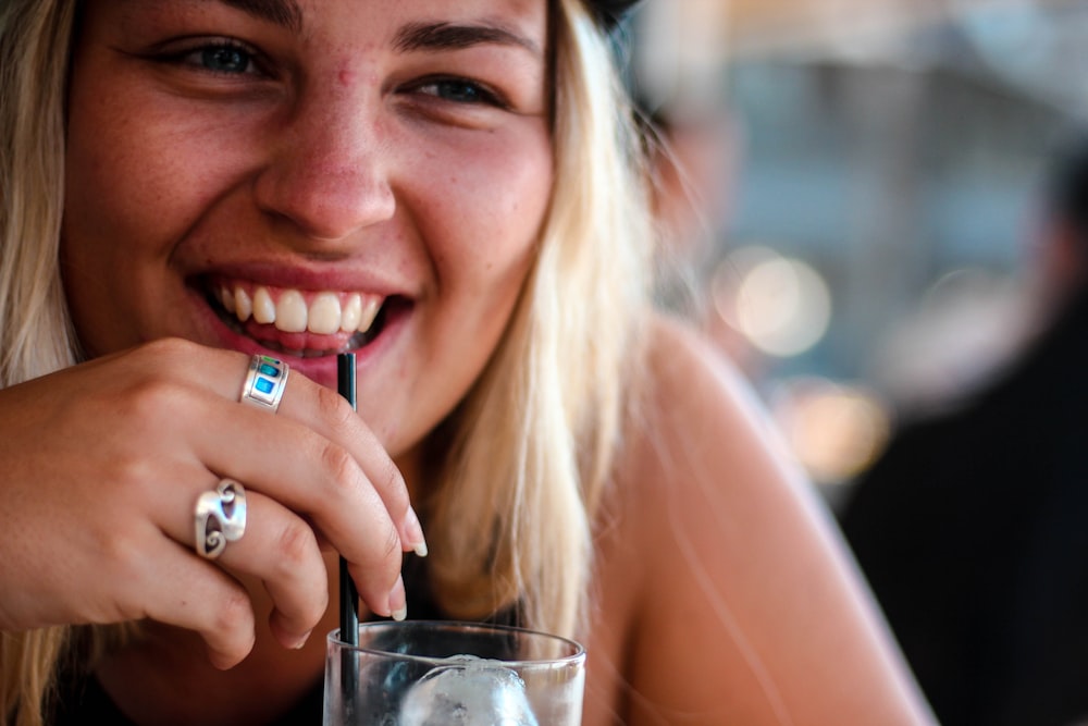 smiling woman sipping on drinking glass