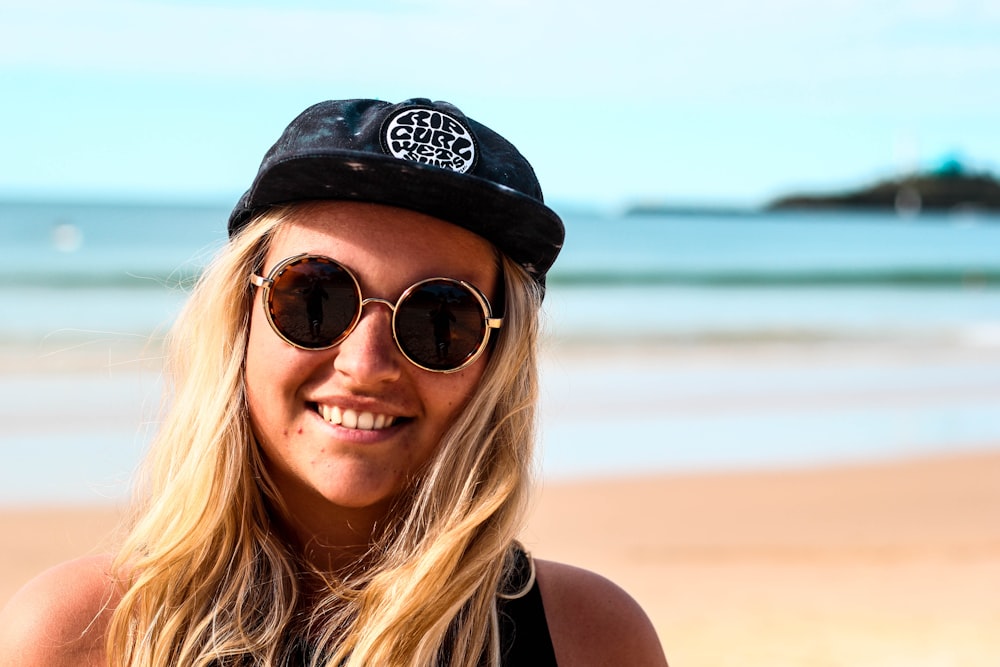 a woman wearing a hat and sunglasses on the beach