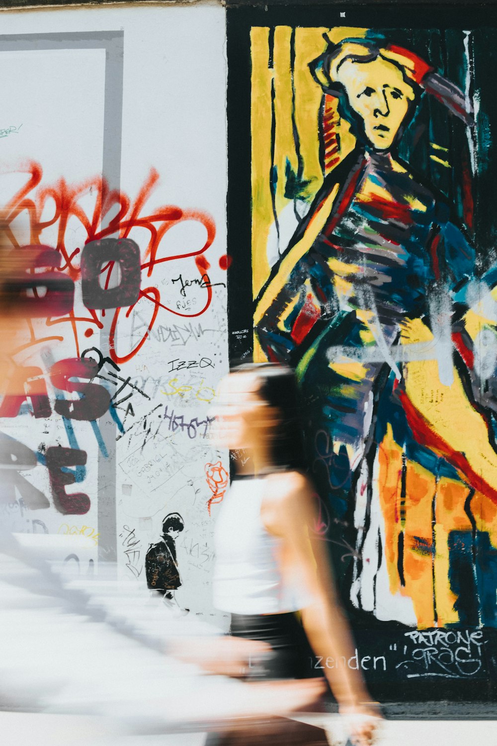 woman in white dress standing in front of wall with graffiti