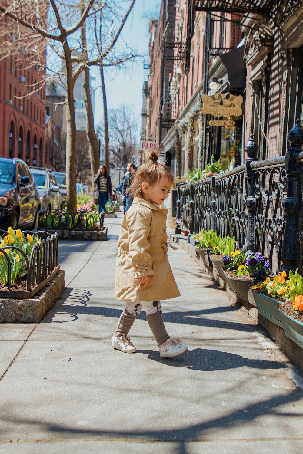 baby wearing jacket walking on concrete pathway near house