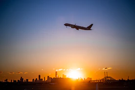 A sleek cargo airplane soaring above clouds at sunset.