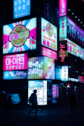 A group of excited travelers dressed in themed gear exploring a neon-lit Seoul street at night.