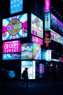 Night view showing the vibrant entrance of Gangnam Dokkaebi Jjeom-O with bright neon lights
