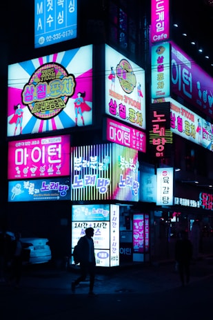 Night view of Gangnam with bright neon signs highlighting the club's location.
