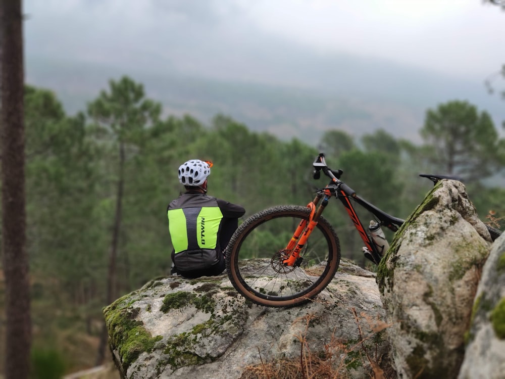 uomo sulla roccia accanto alla bicicletta