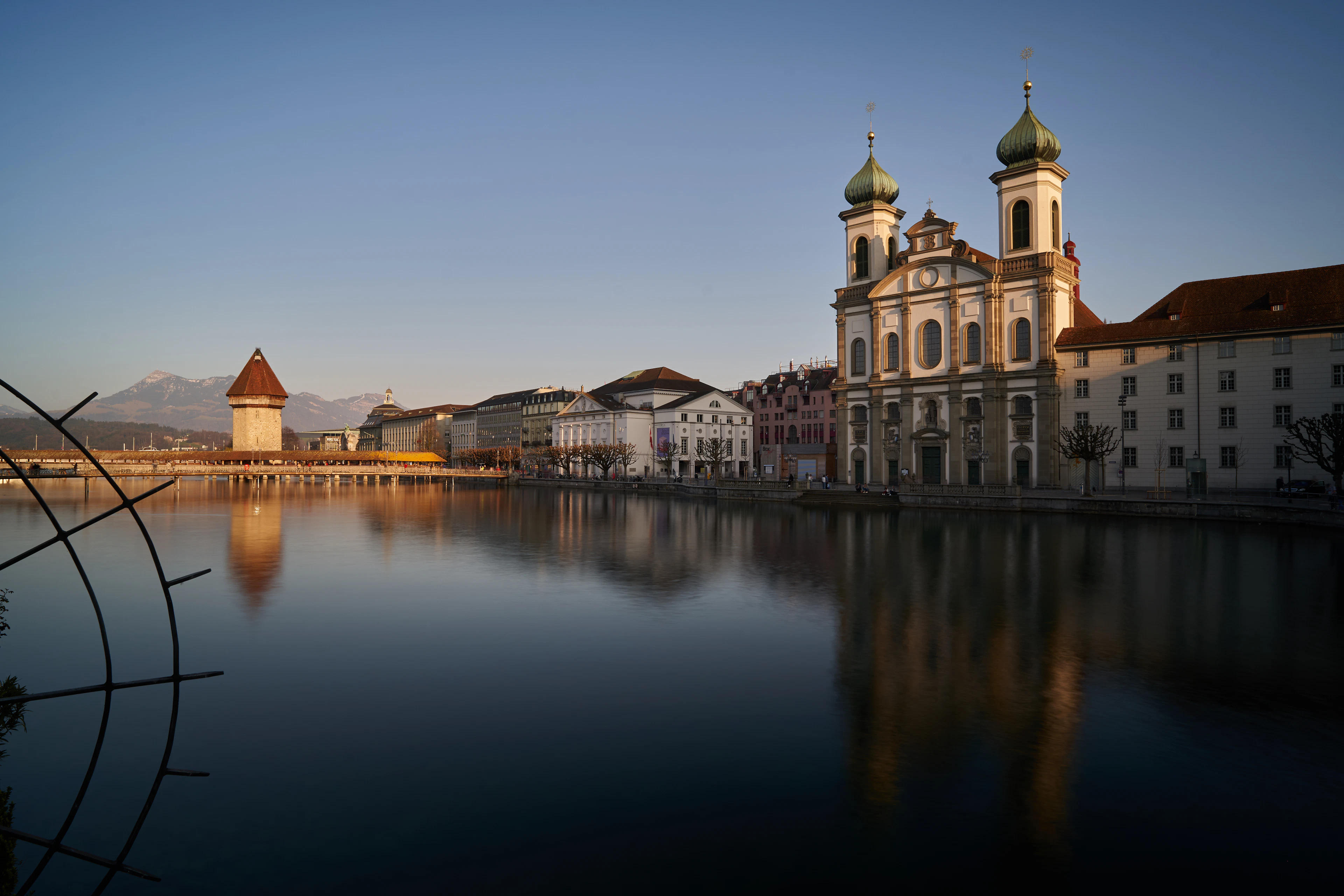 The Water Tower, Chapel Bridge and Jesuit Church towers glow at golden hour, reflected in the Reuss.