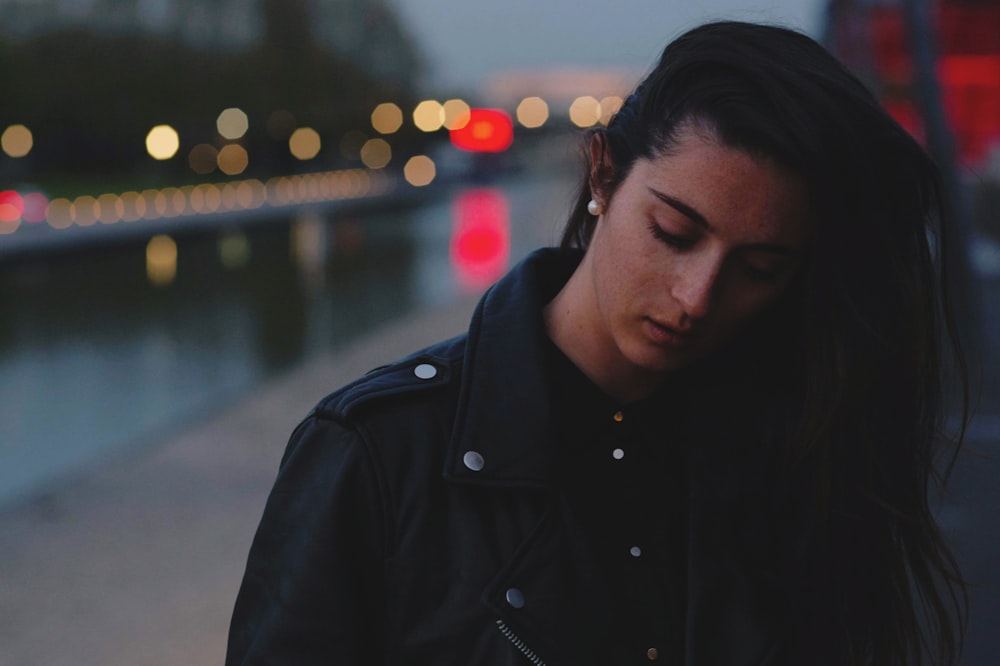 woman wearing black jacket standing near road