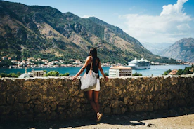 person standing near road looking on sea with different boats on it