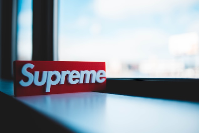 A bright red rectangular object with white text on it is positioned on a windowsill. The background is softly blurred with natural daylight streaming through the window, creating a peaceful and mellow atmosphere inside.