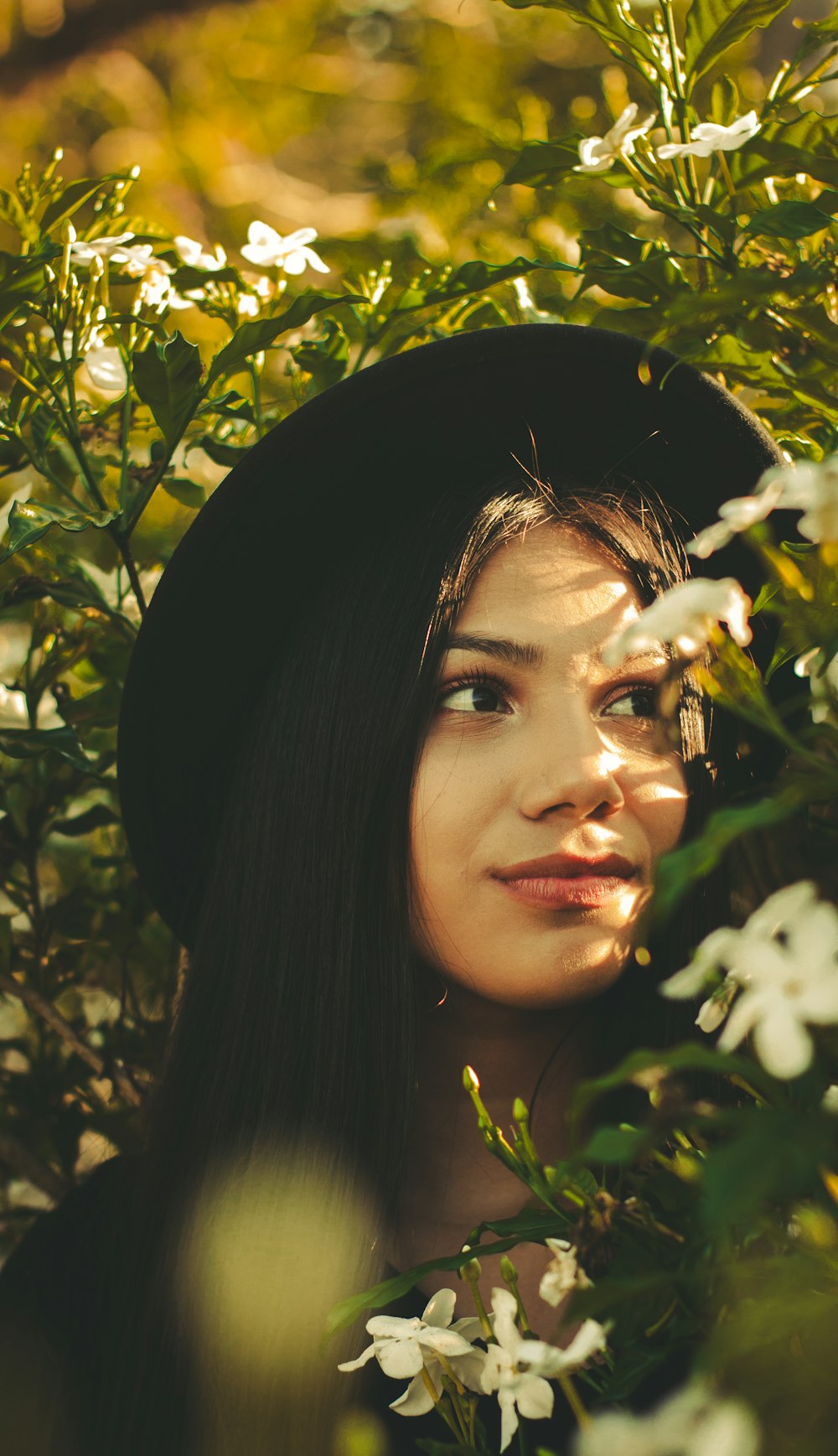 woman in black hat hiding in leaves