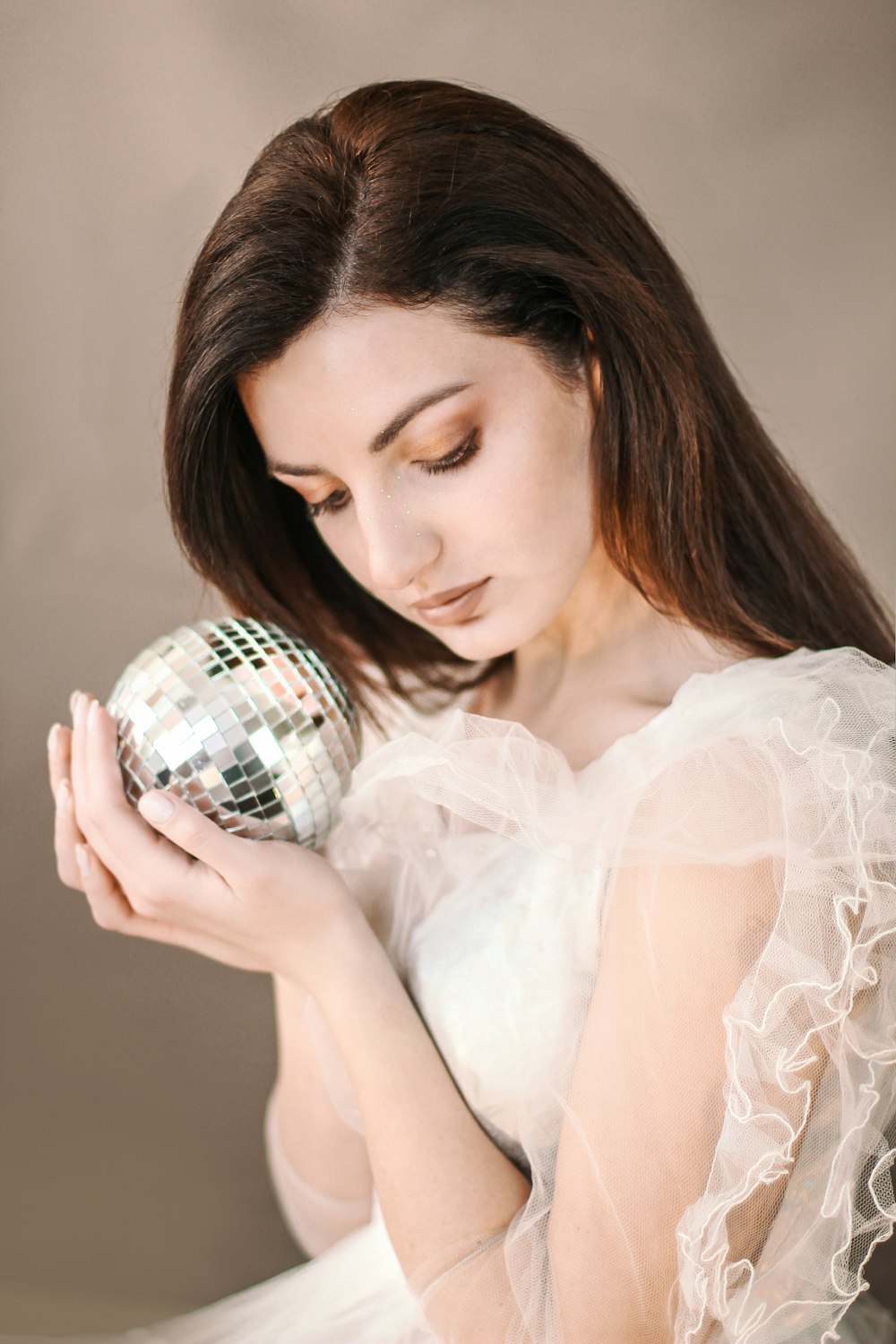 femme tenant une boule disco argentée