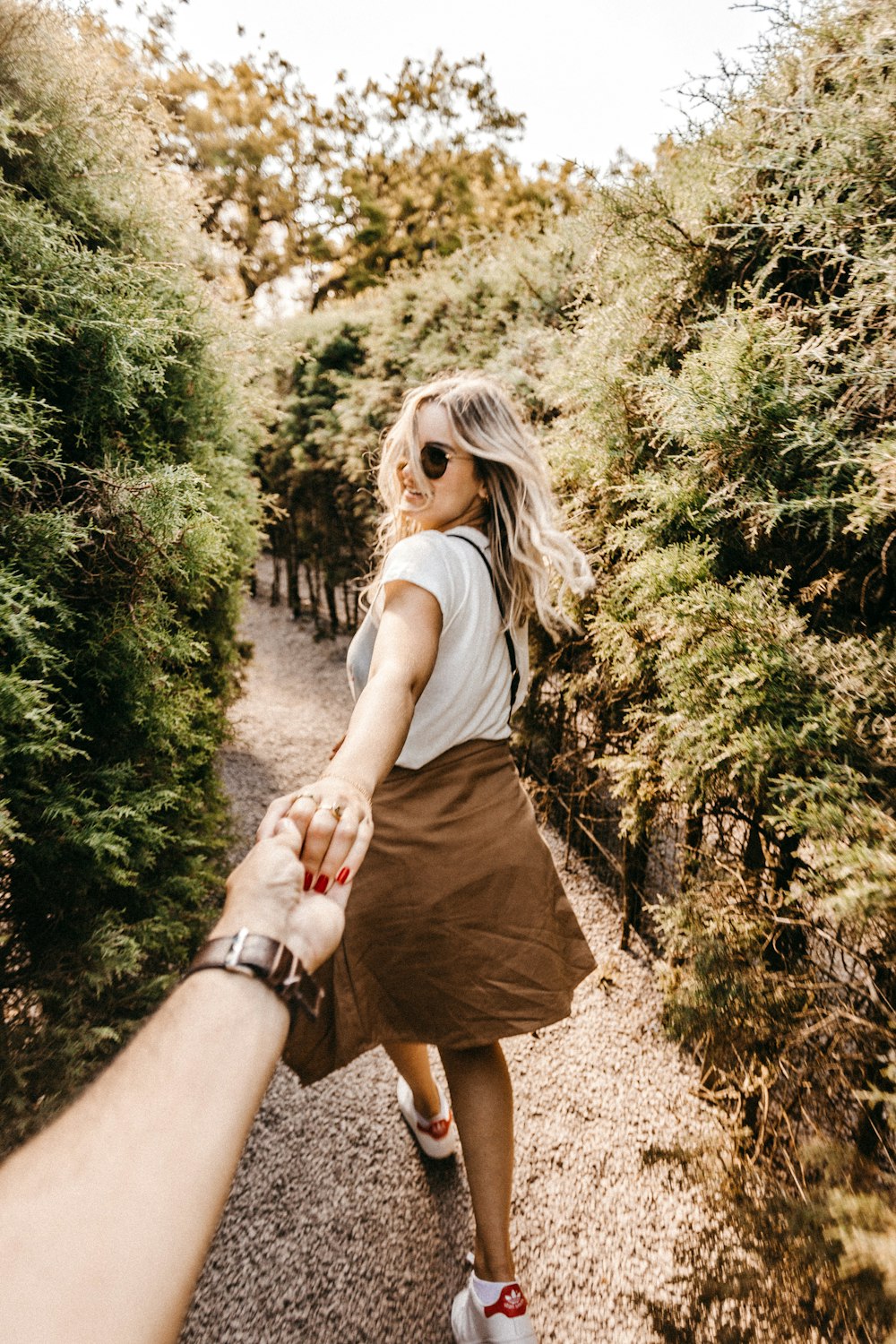 woman holding person's hand near trees