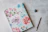 Close-up of a spiral notebook with a floral cover resting on a wooden desk.
