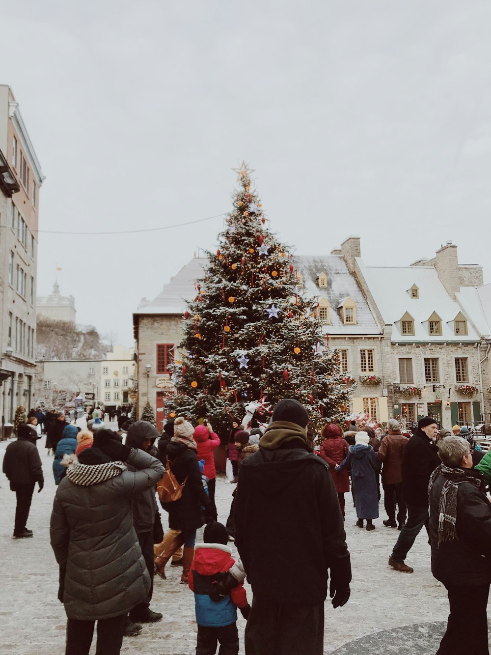 a group of people standing around a christmas tree