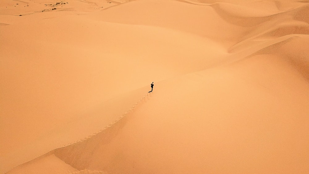 Una persona sola che cammina attraverso le dune di sabbia