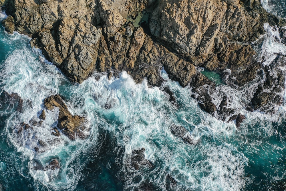 an aerial view of the ocean and rocks