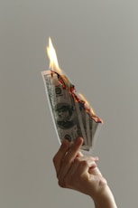 person holding lighted dollar bills