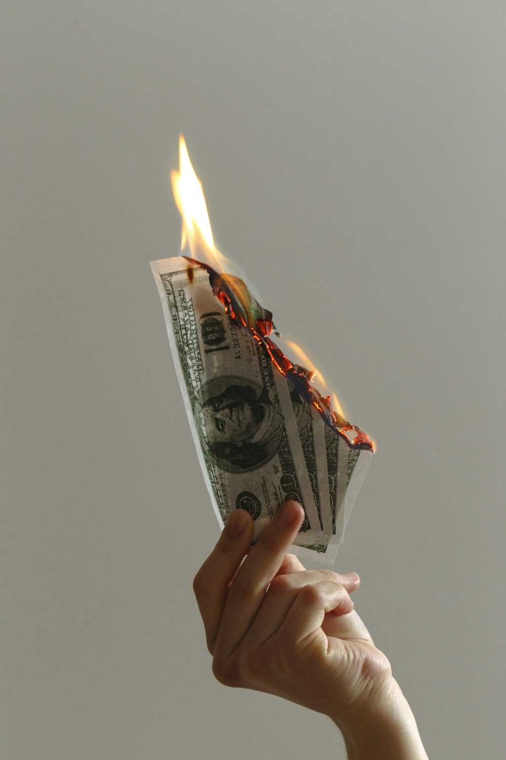 火のついたドル紙幣を持っている人