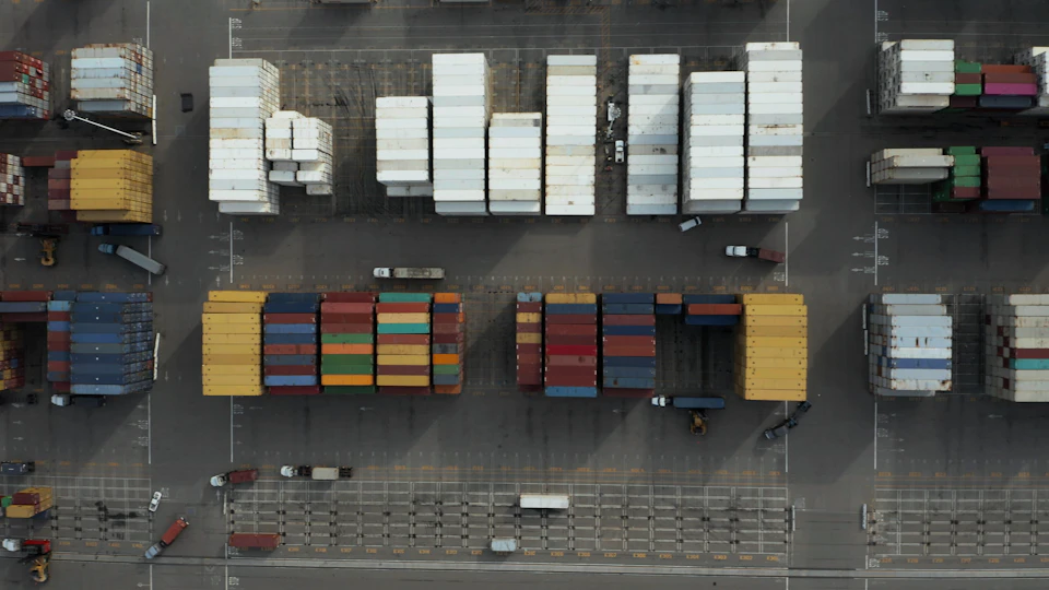 Vibrant cargo containers stacked on trucks at a bustling port with colorful concrete structures