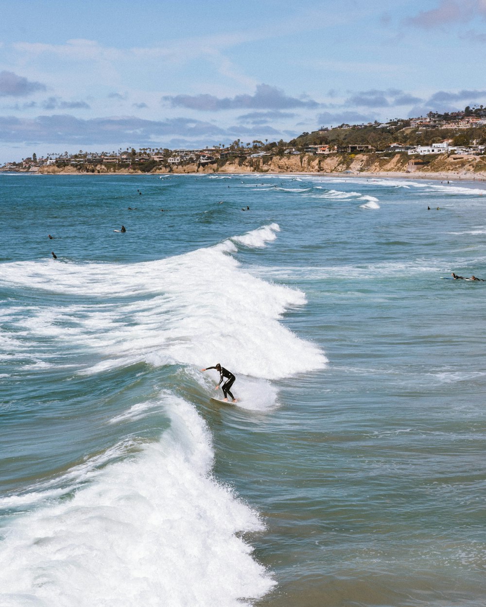 few people surfing on sea during daytime