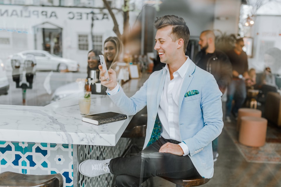 une homme souriant dans un café avec un livre posé sur le comptoir