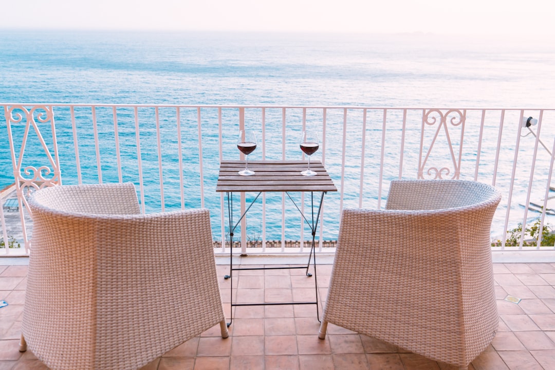 two white wicker chairs in front of blue sea,