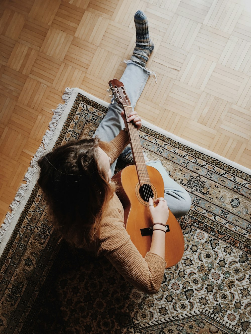 person playing guitar while sitting on area rug