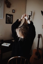 woman in black sweater holding her hair