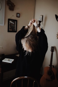woman in black sweater holding her hair