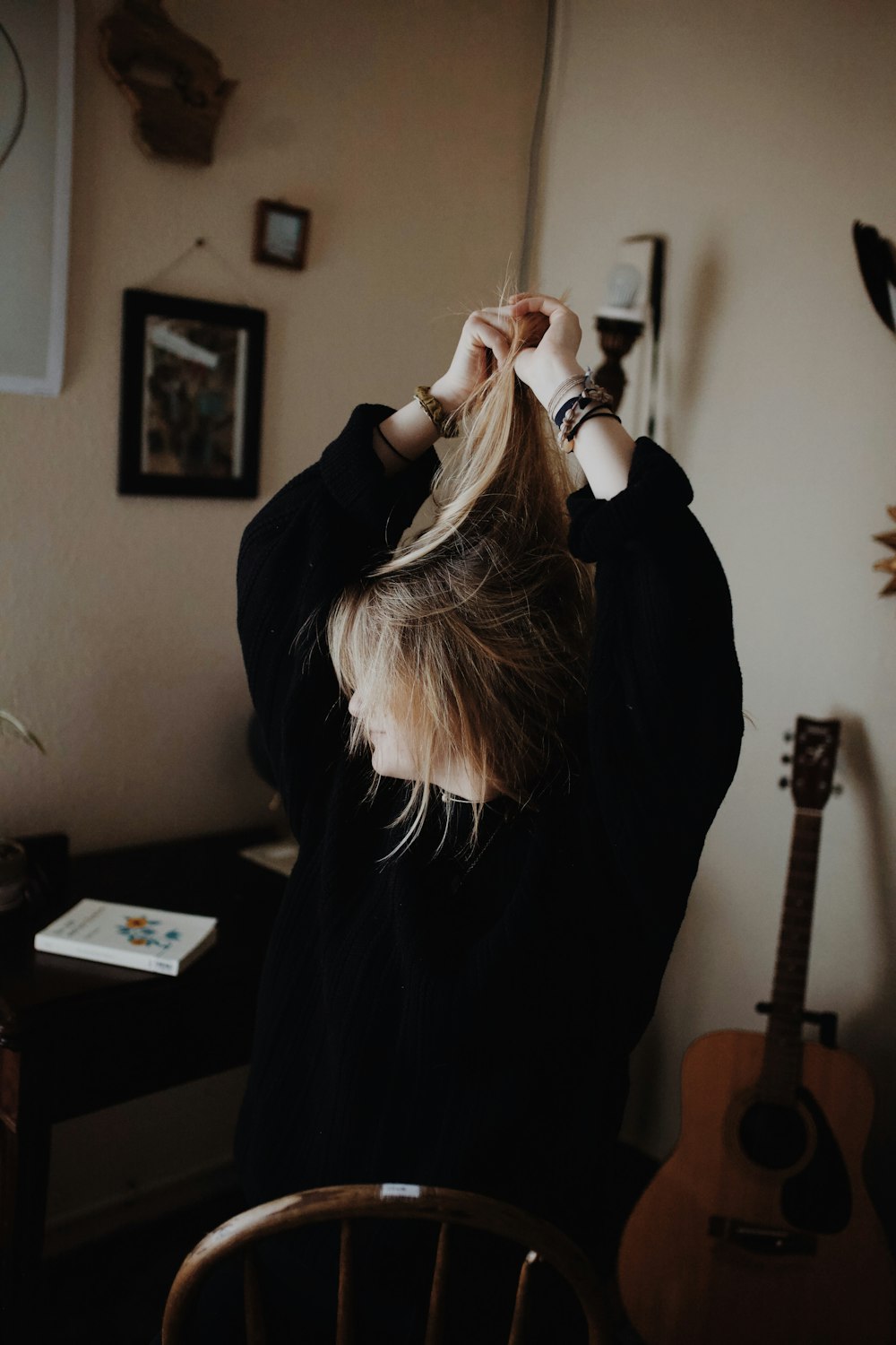 woman in black sweater holding her hair